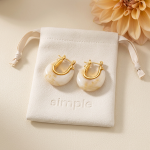 Cream Marble Resin Huggie Earrings on the original simple pouch with an apricot dahlia