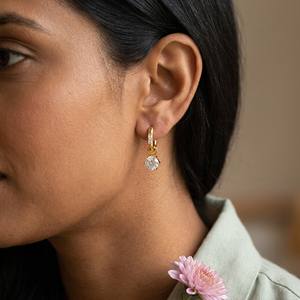 Round zircon drop huggie earring worn on an ear with a pink autumn chrysanthemum