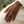 Square natural lifestyle image of a gold hand chain on a woman with deep brown skin