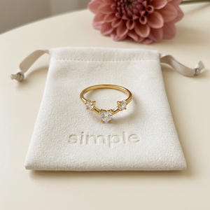 Triple Heart Zircon Ring on the original simple pouch with a dusty-rose dahlia